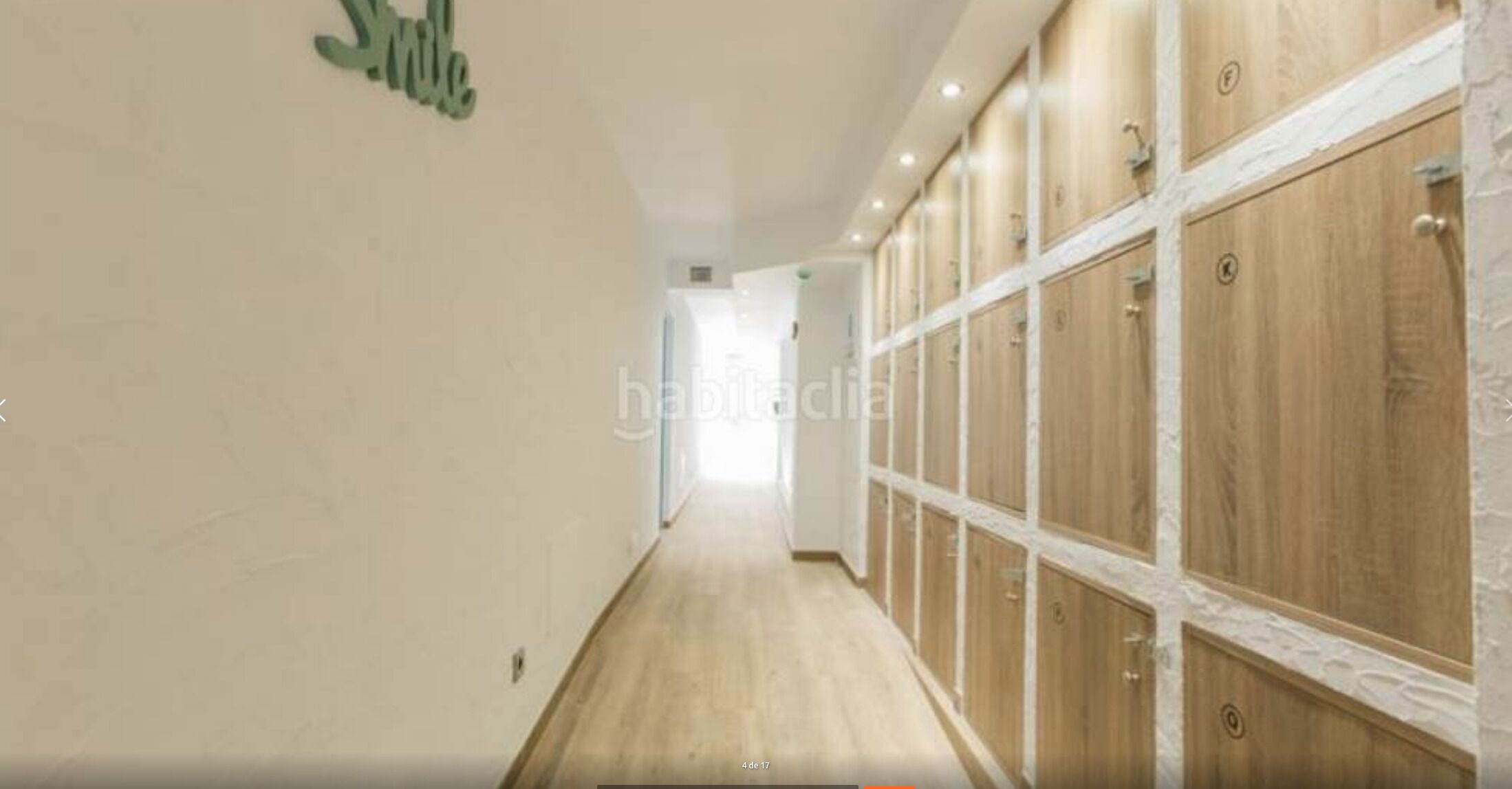 A hallway with wooden lockers on one side and a plain wall on the other.