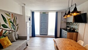Una sala moderna con sofá, mesa de comedor de madera y área de cocina con televisor.