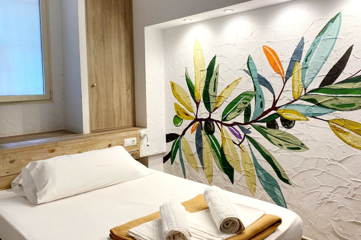 Ein Hotelzimmer mit einem Bett, einem Holzschrank und einer Wand mit einer farbenfrohen Blattform-Mural.