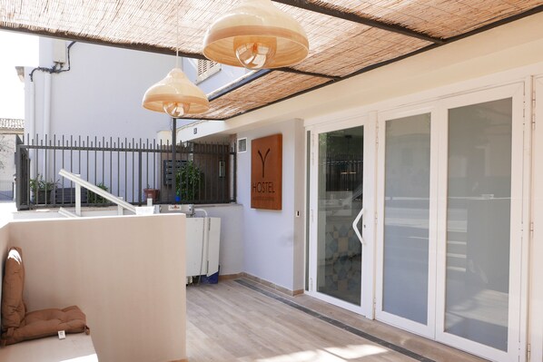 Interior de un hostal con techo de madera, ventanas amplias y un cartel que indica que es un hostal.
