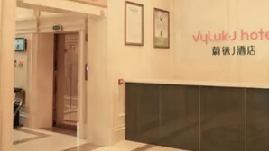 Un hall d’hôtel avec un comptoir d’accueil, un lustre et des tableaux encadrés accrochés au mur.