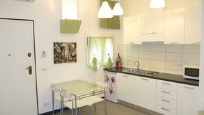 A compact kitchen with a dining table and chairs, a microwave, and a sink.
