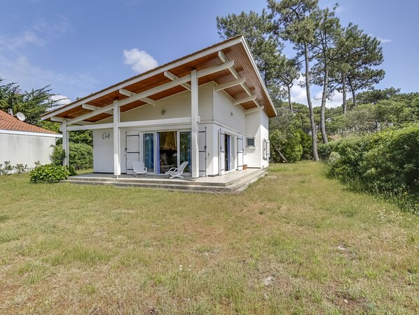 A two-story house with a covered porch, sliding glass doors, and a small garden area.