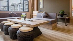 Un soggiorno moderno con divano, tavolino da caffè e vista sugli edifici attraverso ampie finestre.