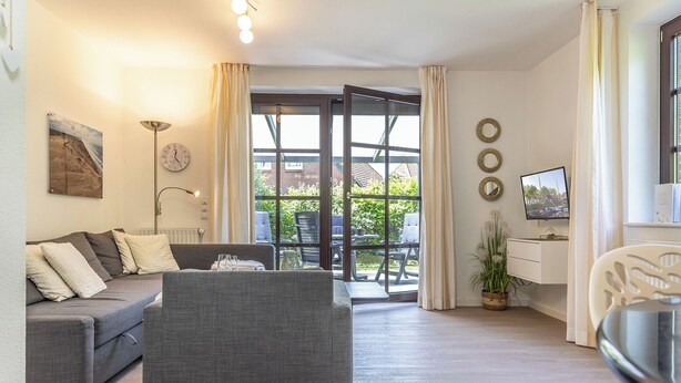Una sala de estar con sofá, una silla, televisor y un comedor con mesa y sillas.