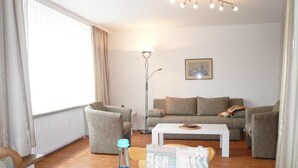 A living room with a sofa, armchairs, a coffee table, and a floor lamp.