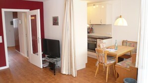 A compact living space with a dining area, kitchenette, and a television.