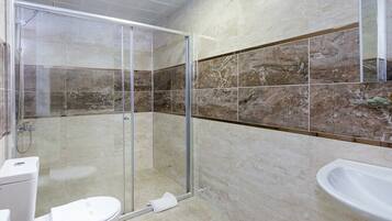 Un baño con ducha de vidrio, inodoro y lavamanos.