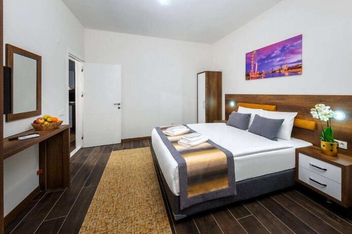 Una habitación de hotel con cama, mesita de noche y un cuadro en la pared.