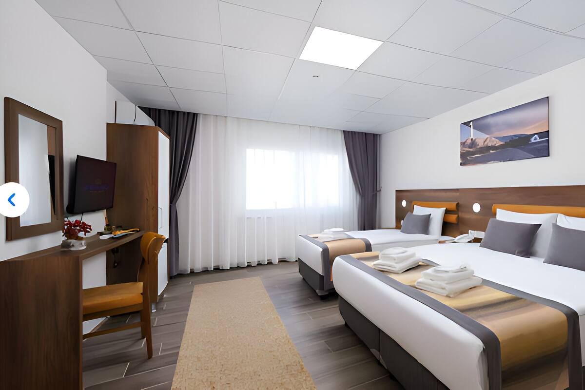 Habitación de hotel con una cama grande, un escritorio con una computadora, un televisor y un cuadro en la pared.
