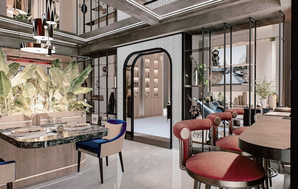 A modern interior with a dining area featuring a marble table and chairs, a large potted plant, and a view through a glass door. - River Elite Hotel & Spa (Antalya)