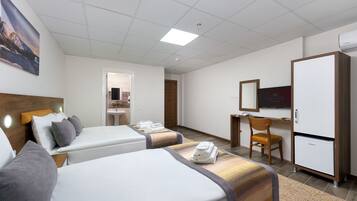 A hotel room with two beds, a desk, a chair, a television, and a refrigerator.