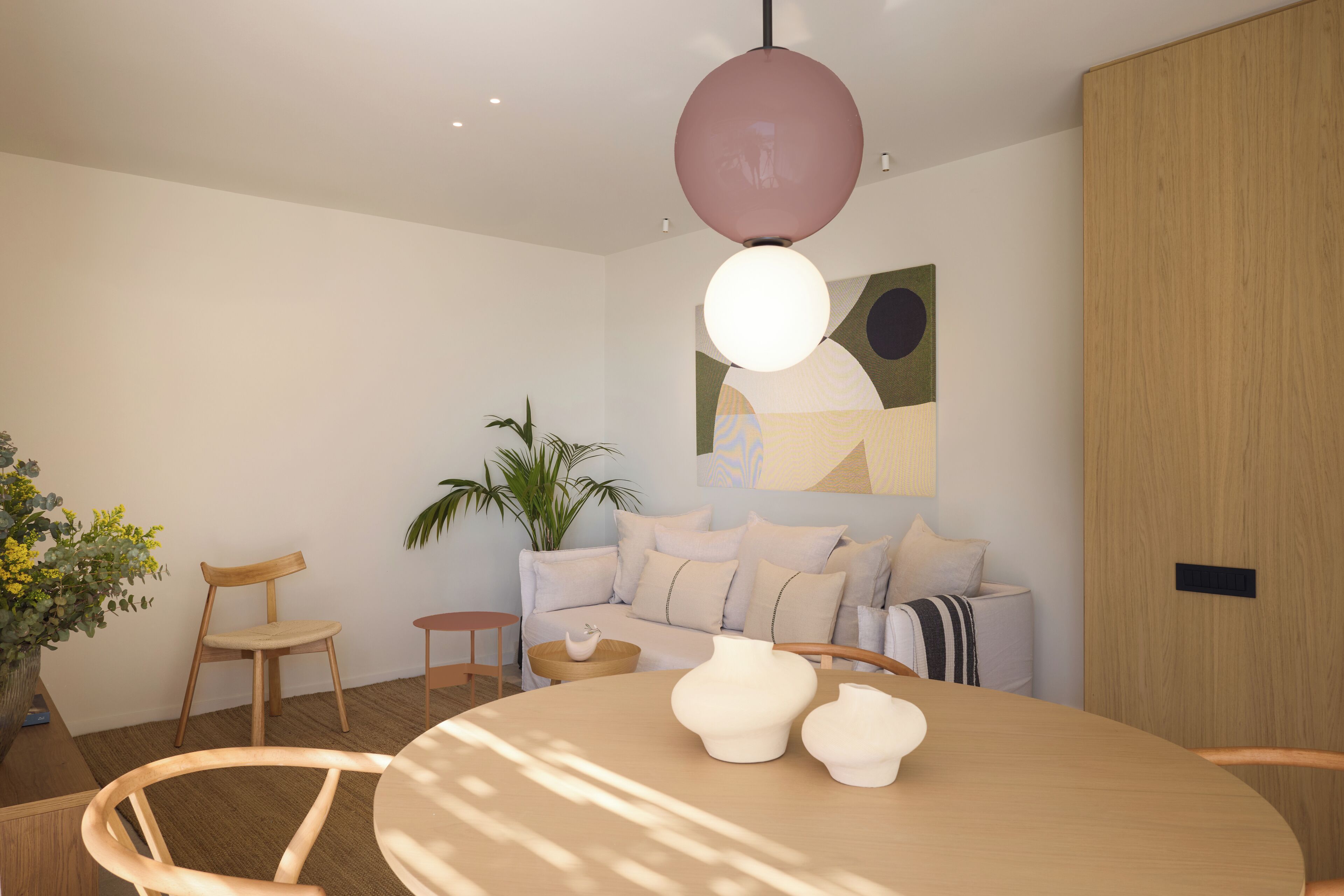 Um quarto moderno e bem iluminado, com uma mesa redonda, cadeiras, um sofá e um grande quadro abstrato na parede.