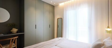 A bedroom with a bed, a desk, a chair, a mirror, and a ceiling fan.
