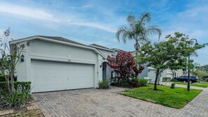 Une maison d’habitation avec un garage, une allée pavée et une pelouse bien entretenue.