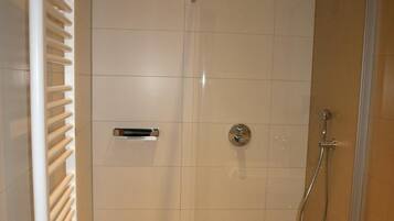 A modern bathroom with a glass-enclosed shower, a white toilet, and a towel rack.