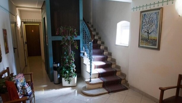 A staircase with a blue railing, a potted plant, and a framed picture on the wall. - Villa Mulino (Garda)
