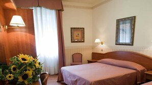 A hotel room with two beds, a desk with a lamp, and a chair. - Villa Mulino (Garda)