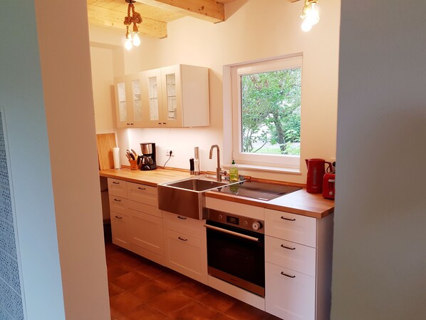 A modern kitchen with white cabinets, a stainless steel sink, and a built-in oven.