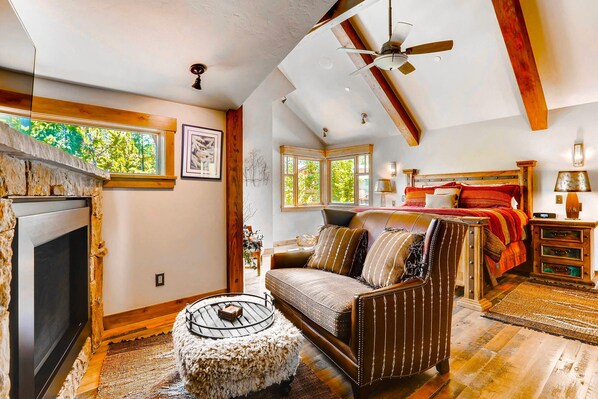 A cozy room with a fireplace, a sofa, a bed, and a ceiling fan. - A Mine Shaft (Breckenridge)