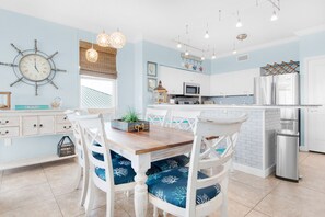 A kitchen with white cabinets, a wooden table, and blue chairs with white patterns.