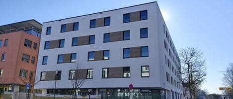 Un immeuble à étages doté d’une architecture moderne, caractérisé par une série de fenêtres et de balcons.
