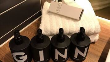 Une salle de bain avec un comptoir en bois, une serviette blanche et quatre récipients noirs étiquetés G, G, I, N, N.