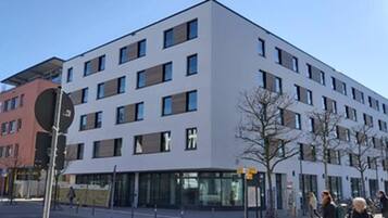 A modern multi-story building with a flat facade, large windows, and a ground-level entrance.