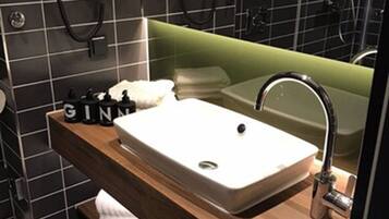 A modern bathroom with a large sink, a mirror, and a shower area.