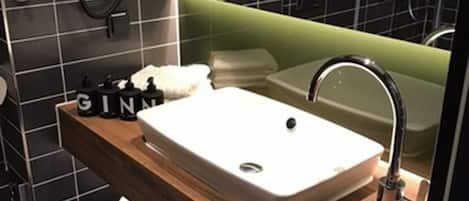 Un baño moderno con un lavamanos grande, un espejo y una zona de ducha.