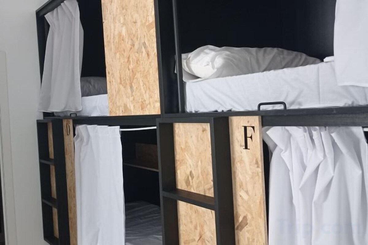 A bunk bed with a wooden frame and white bedding.