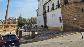 Un edificio histórico con una torre de reloj, una chimenea alta y una fachada blanca con balcones.