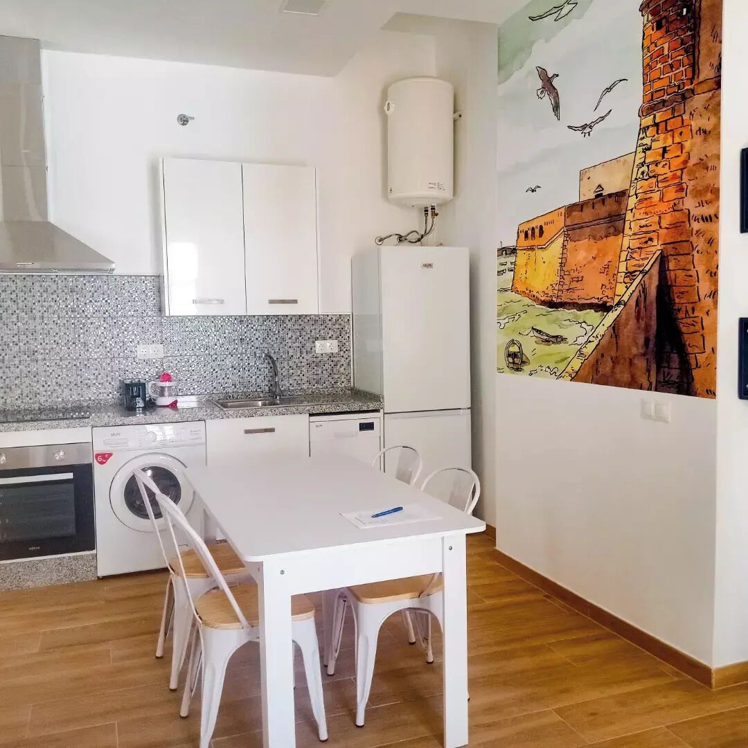 A compact kitchen with white cabinets, a built-in washing machine, and a water heater.