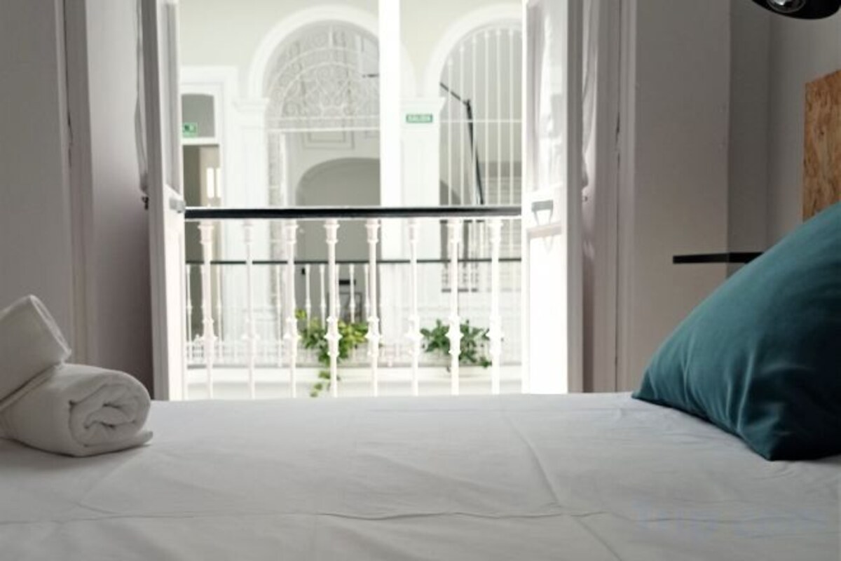 Ett hotellrum med en säng, en vit handduk och en balkong med ett räcke.