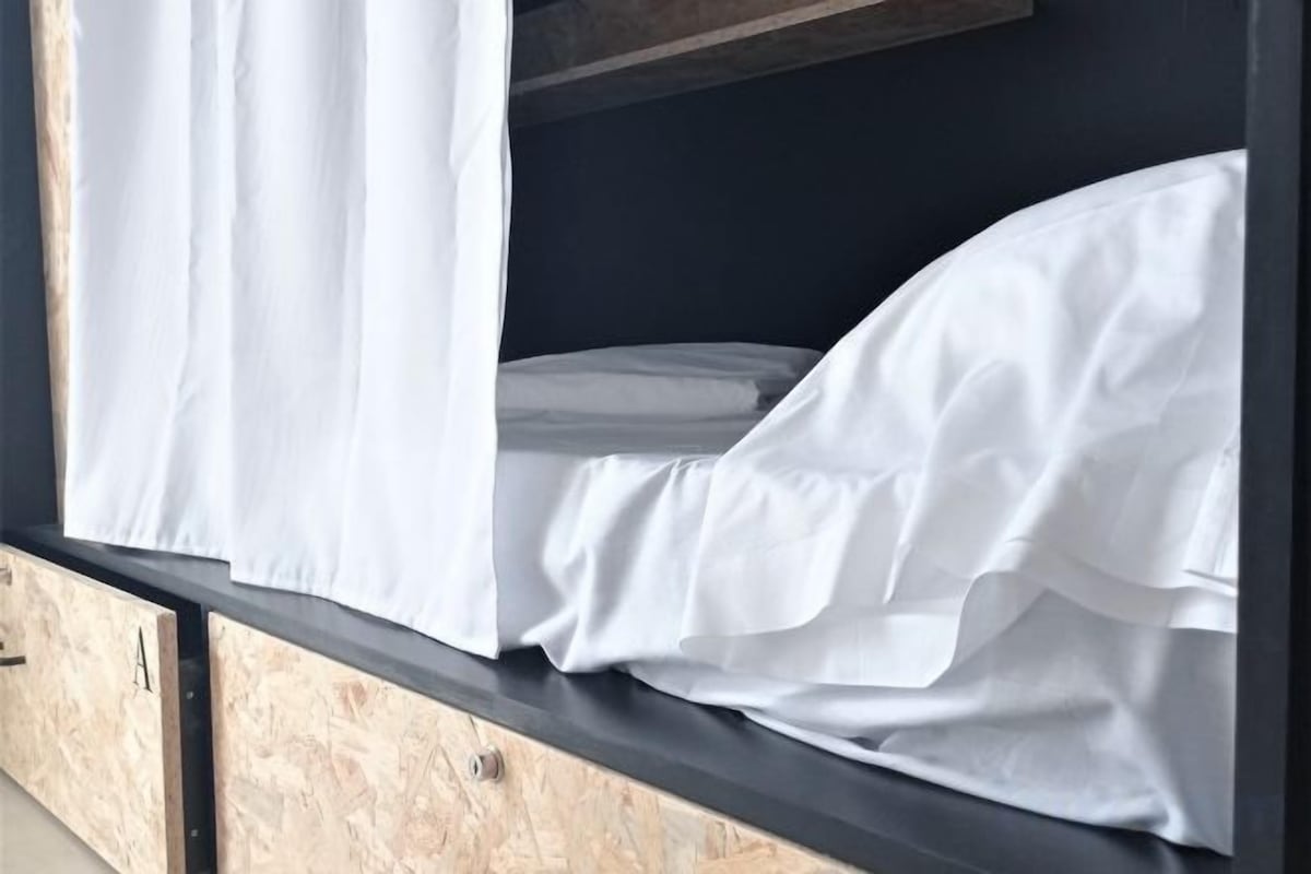Un lit superposé avec une literie blanche et une tête de lit en bois.