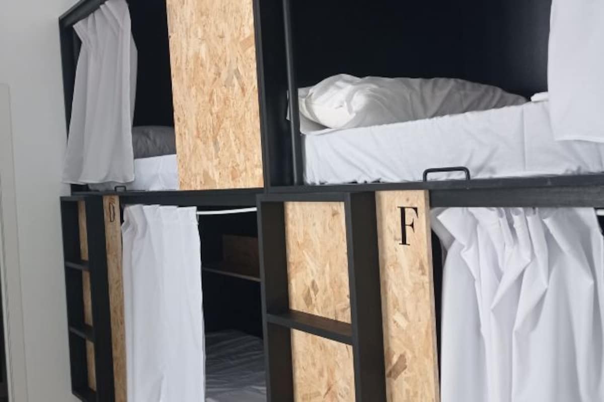 Una cama litera con ropa blanca y paneles de madera.