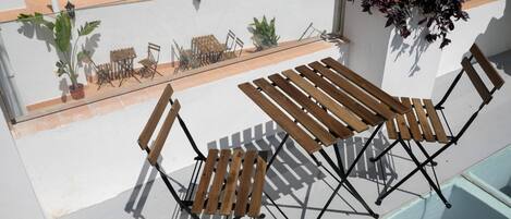 A balcony with wooden furniture, potted plants, and a hanging plant.