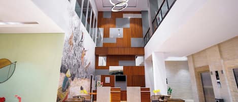 A modern lobby with a high ceiling, a central staircase, and a reception desk.