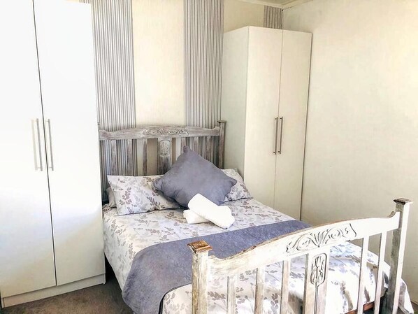 Quarto com cama, guarda-roupa e mesa de cabeceira.
