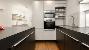 A modern kitchen with black countertops, white cabinets, and stainless steel appliances. - Gorgeous house in the heart of Chelsea (London)