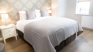 A neatly arranged bedroom with a bed, bedside tables, and a window. - Citystay Living - Hinton House (Cambridge)