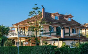 A large, two-story house with a tiled roof, a balcony, and a chimney.