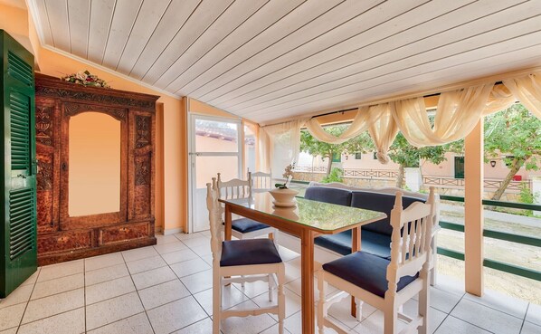 A dining area with a wooden table and chairs, a decorative wooden door, and a view of the outdoors.