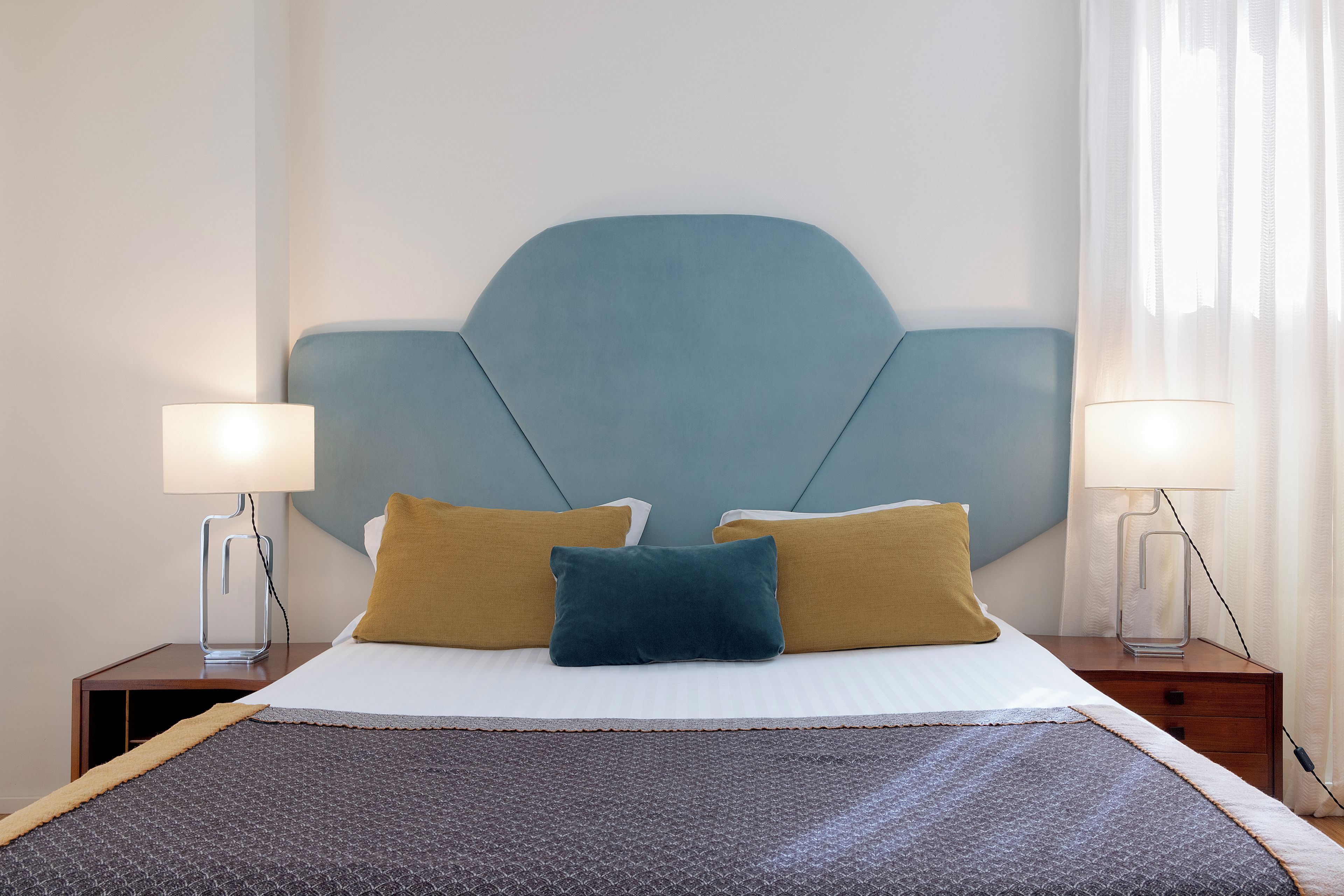 Une chambre d’hôtel avec un lit, deux lampes de chevet et une tête de lit.