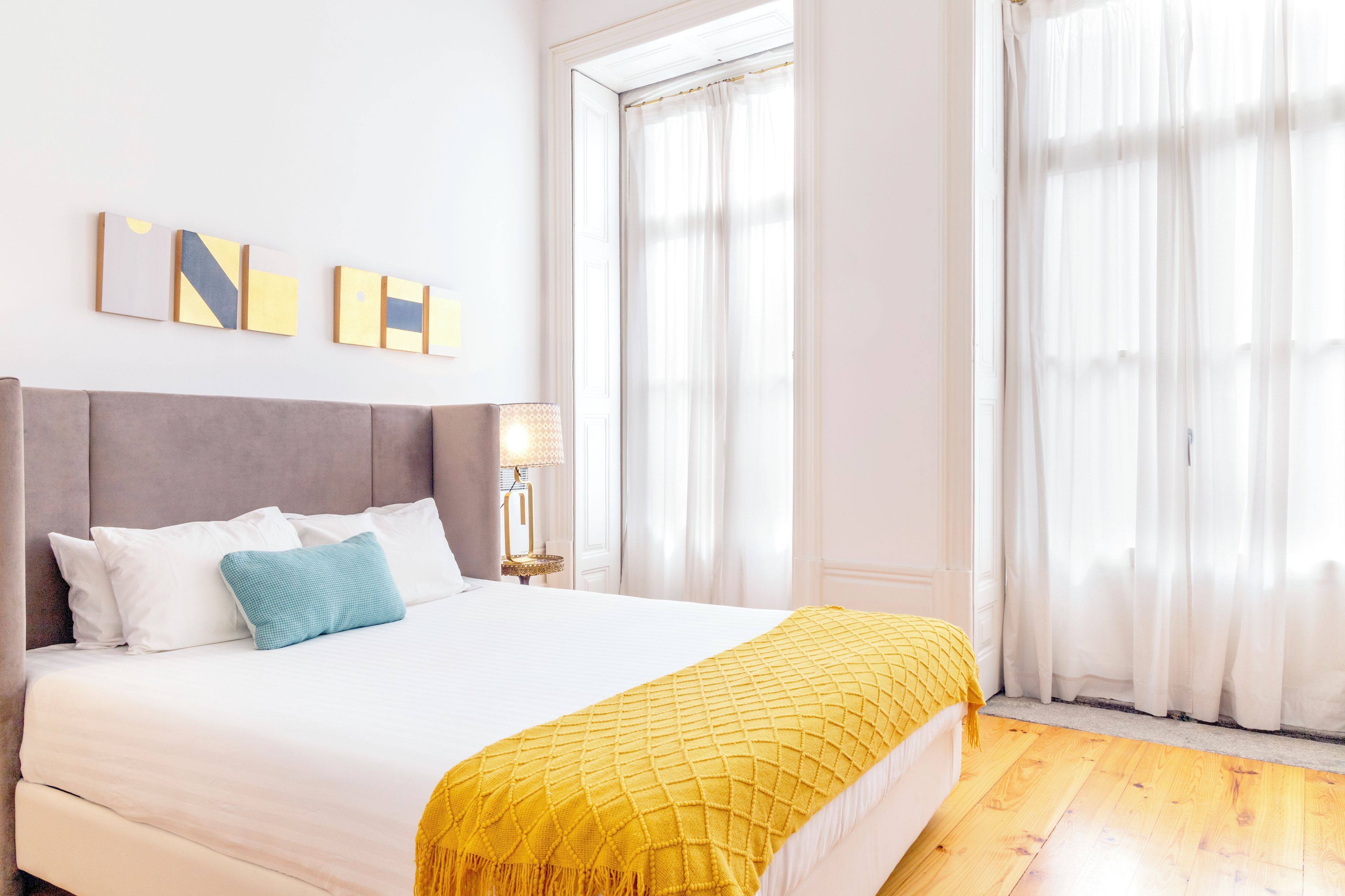Una habitación de hotel con una cama, una mesita de noche, una lámpara y una ventana con cortinas.
