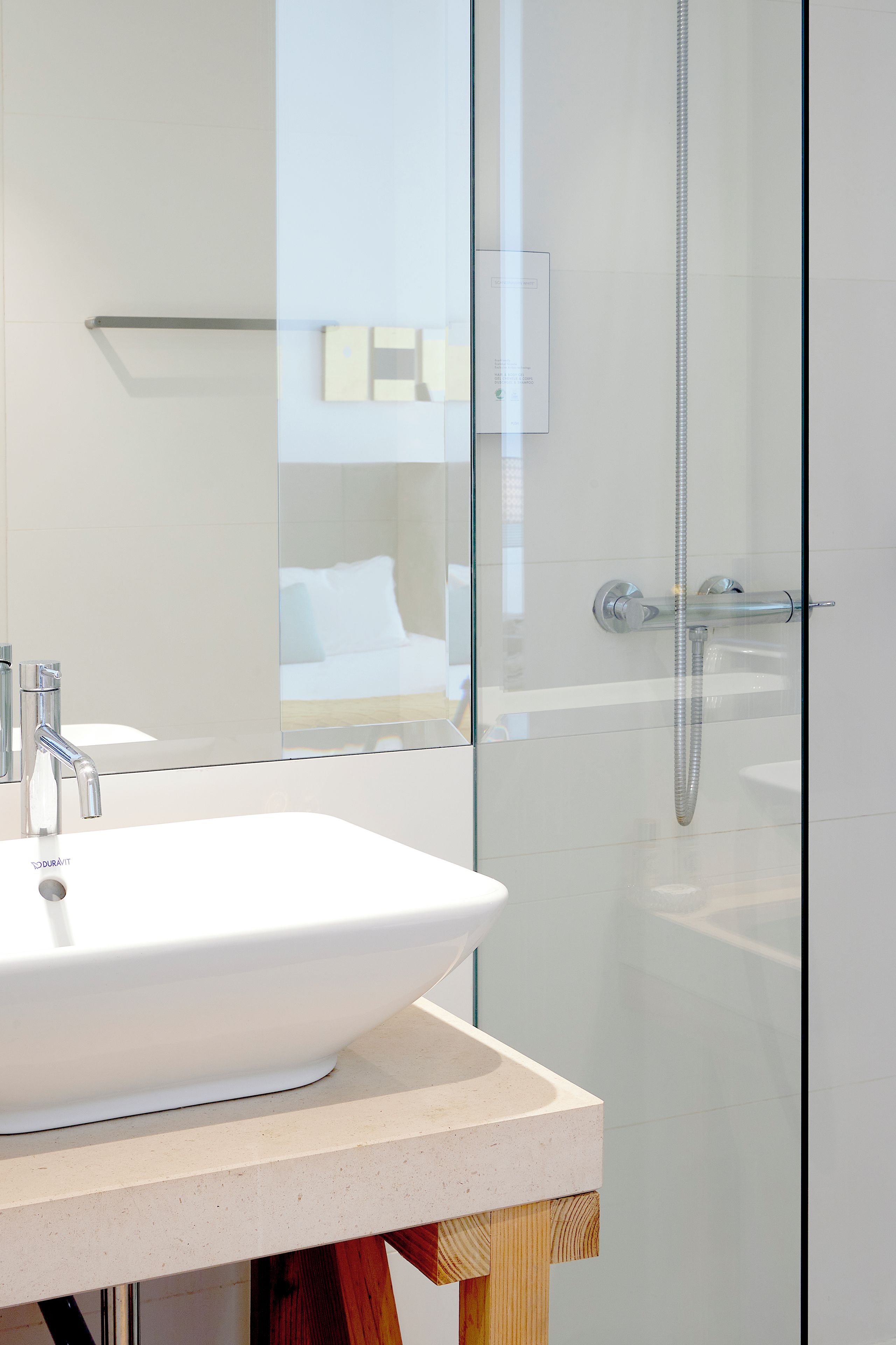 A modern bathroom with a white sink, a glass shower enclosure, and a visible shower head.