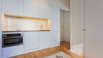 Een moderne keuken met witte kasten, een inbouwoven en een houten aanrecht.
