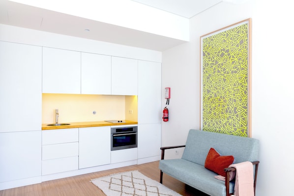 A compact kitchen with white cabinets, a built-in oven, and a small sink. - The Art Porto (Porto)
