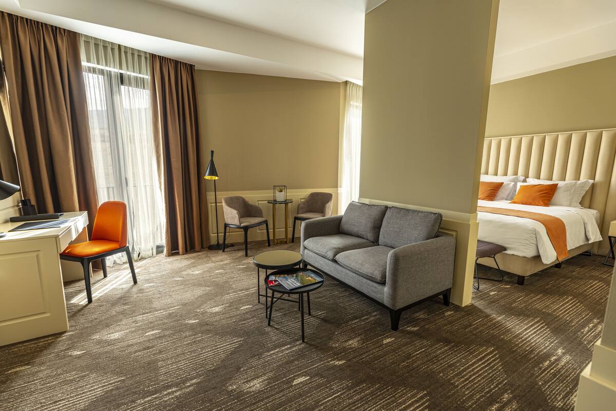 A hotel room with a bed, a sofa, a desk, and a chair.