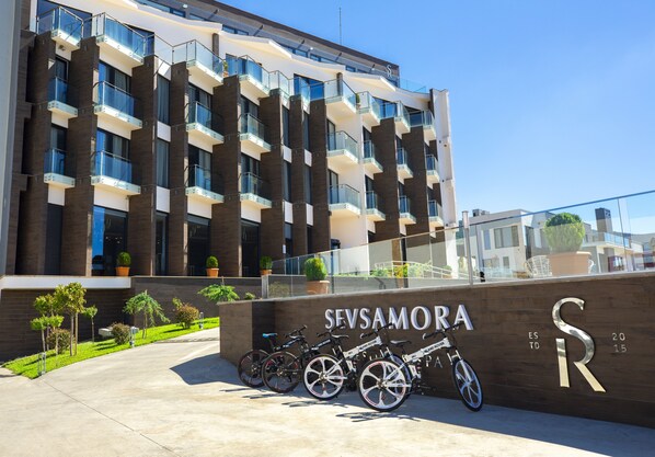 A modern building with a sign reading "SEVSAMORA" and a row of bicycles parked in front.